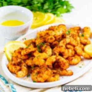 Finished Air Fryer Cajun Shrimp in a bowl, garnished with parsley and lemon.