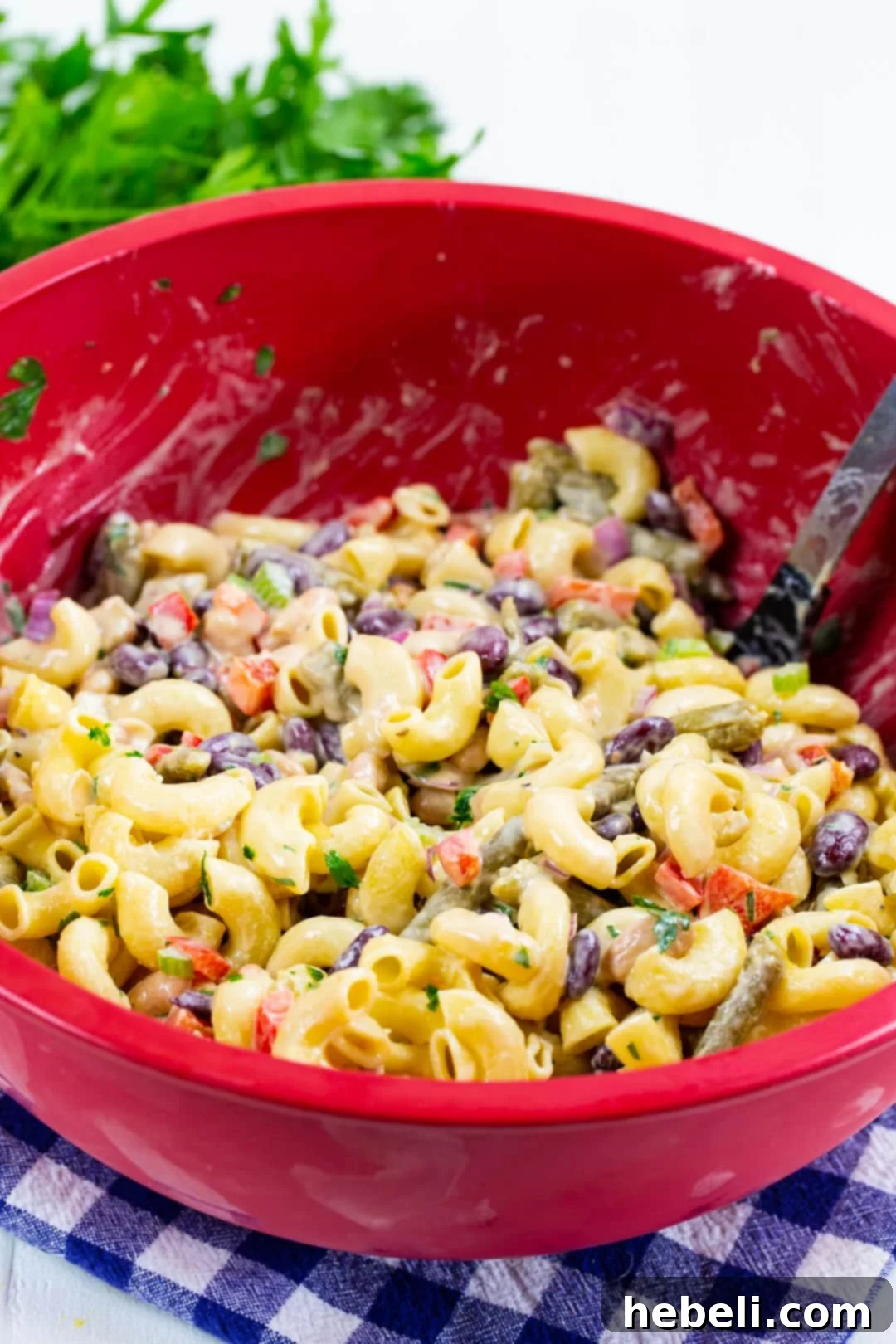 Hearty Three Bean Pasta Salad 3 Pasta salad ingredients being mixed in a large bowl, showing the vibrant colors of beans, pasta, and vegetables before dressing is fully incorporated.