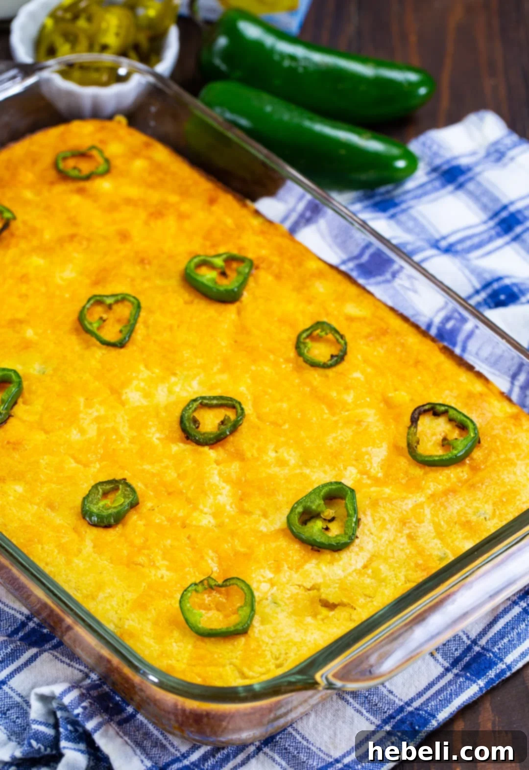 A freshly baked 9x13-inch baking dish filled with golden-brown Texas-Style Jiffy Cornbread, topped with melted cheese and vibrant sliced jalapenos, fresh from the oven.
