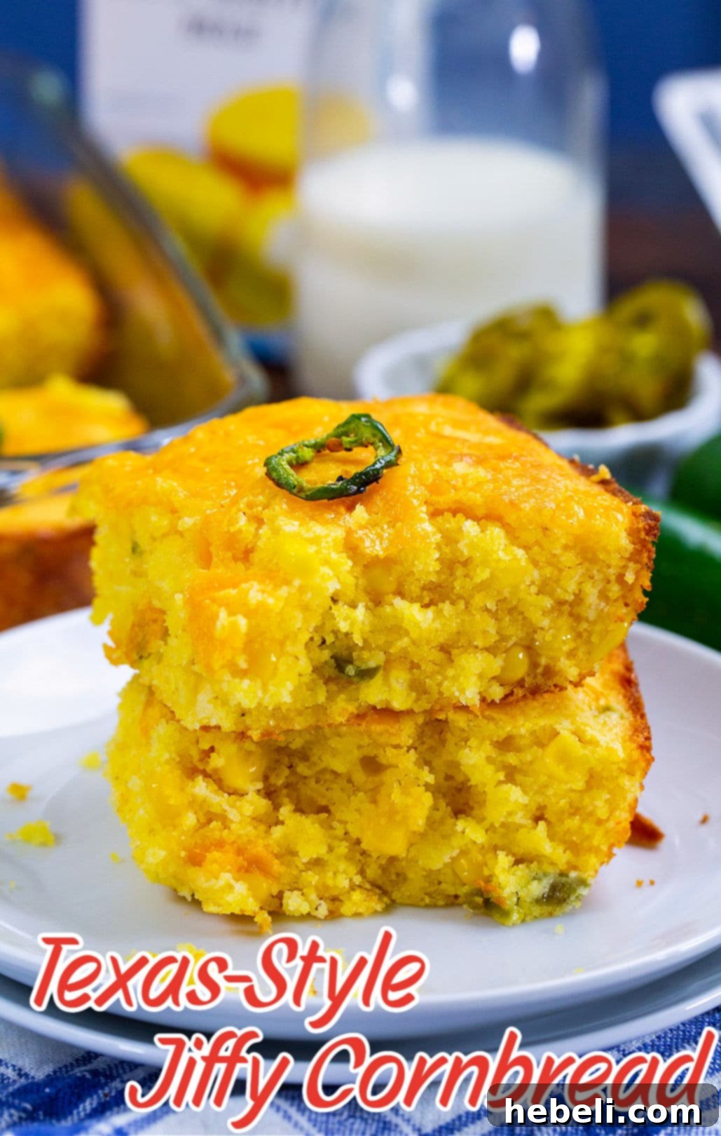 Two pieces of golden Texas-Style Jiffy Cornbread stacked on a small white plate, adorned with a few fresh jalapeno slices, highlighting its appealing presentation.