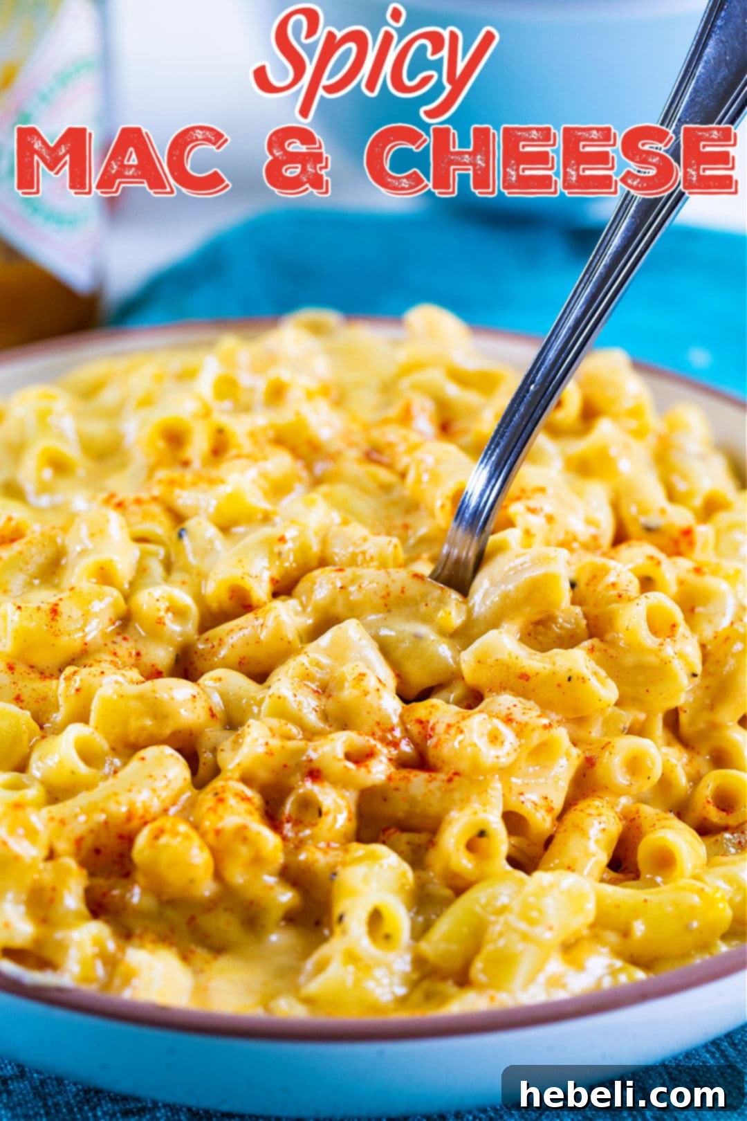 A fork lifting creamy Spicy Mac and Cheese from a bowl, highlighting its perfect texture.