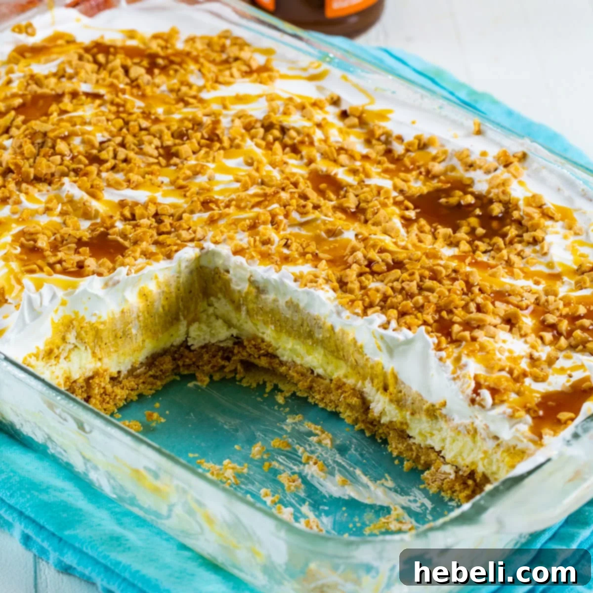 Decadent Pumpkin Delight 2 A beautifully layered Pumpkin Lush dessert in a 9x13-inch glass baking dish, ready to be served, garnished with caramel and toffee bits.