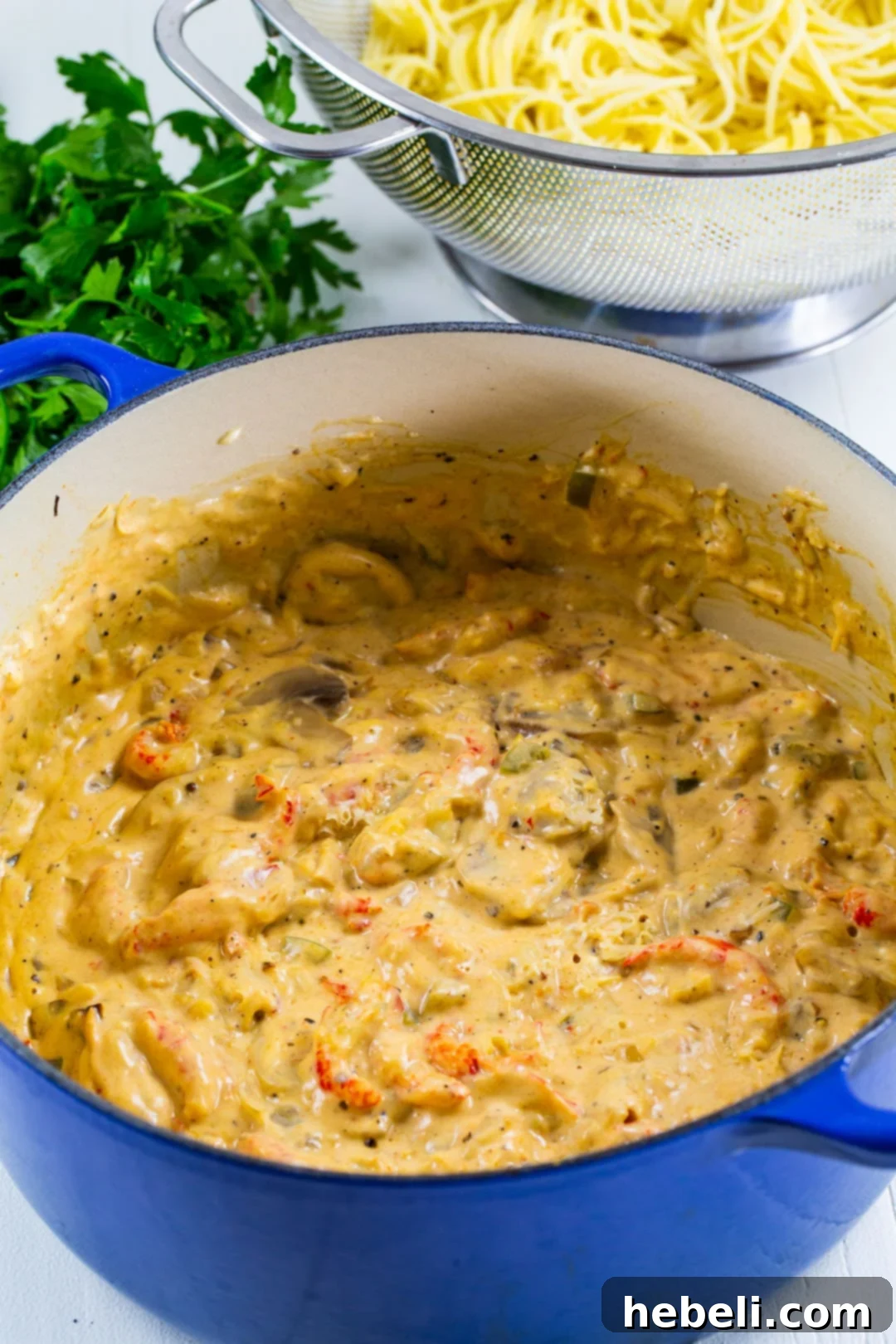The creamy Tetrazzini sauce simmering to perfection in a Dutch oven, featuring mushrooms, bell peppers, and onions, ready for the crawfish.