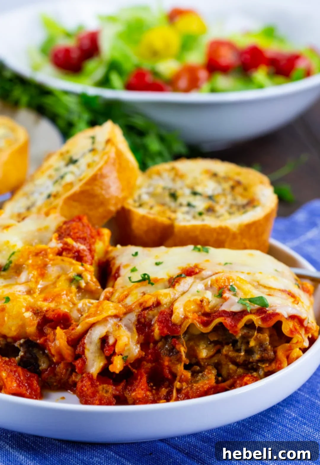 A single Italian Sausage Lasagna Roll-Up served on a plate with crispy garlic bread and a fresh garden salad.