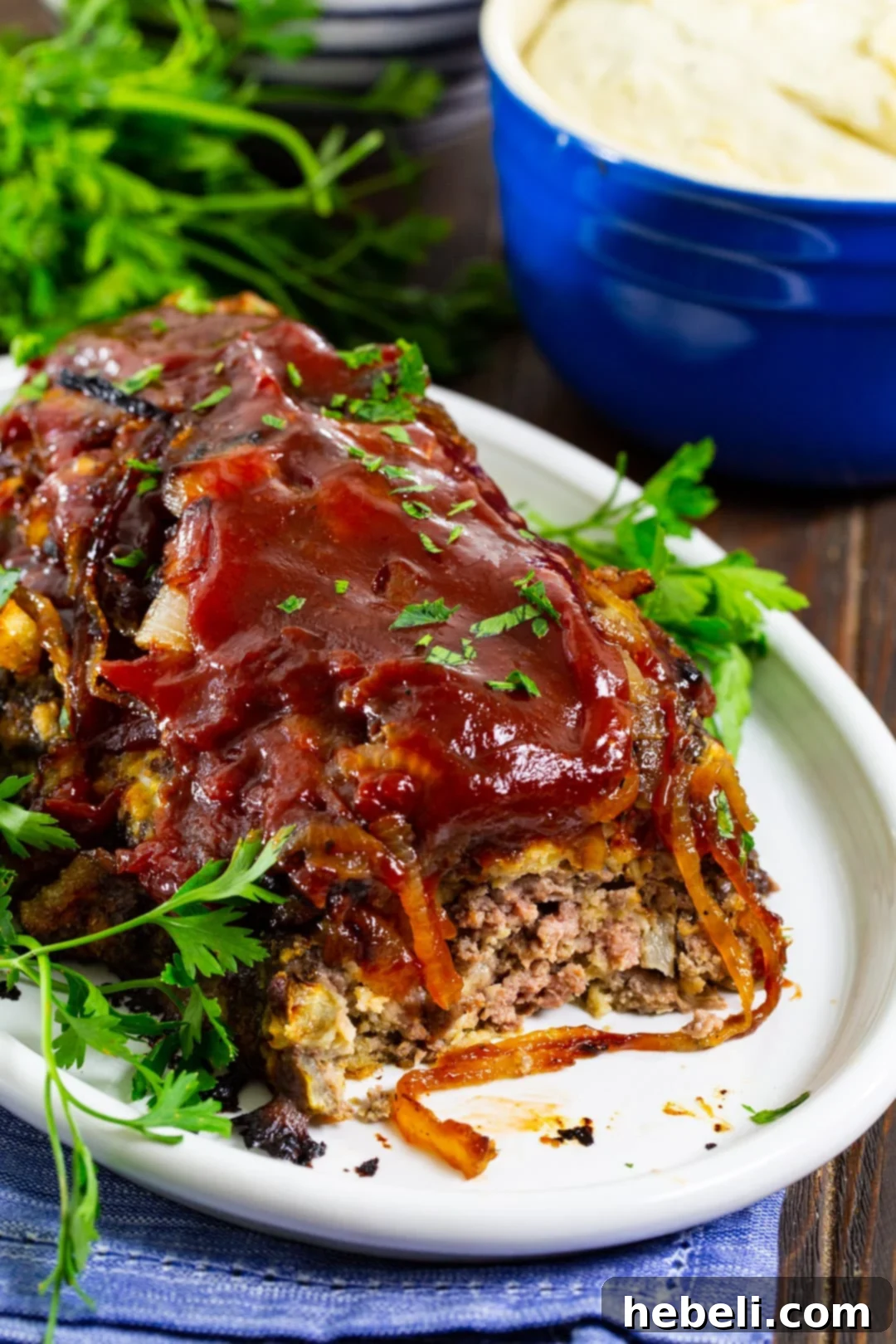 Sweet & Savory Caramelized Onion Meatloaf 4 A slice of Caramelized Onion Meatloaf revealing its moist interior, served alongside mashed potatoes.
