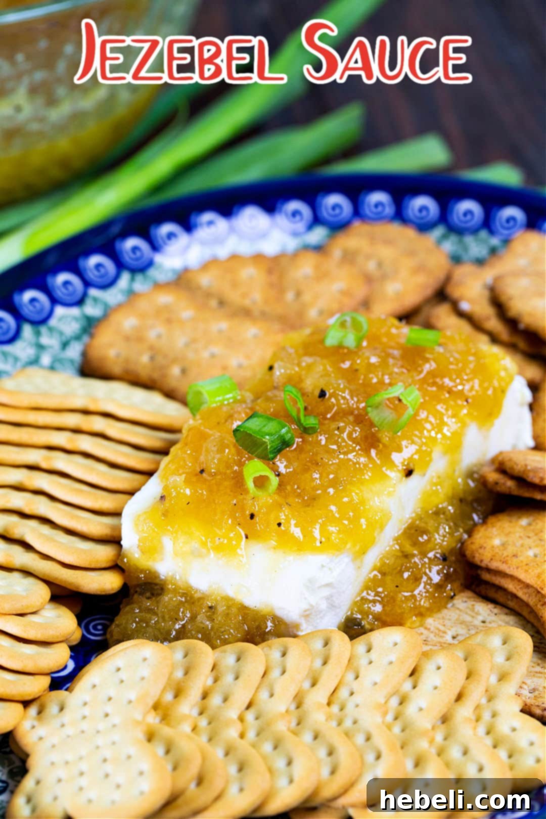 A close-up shot of vibrant Jezebel Sauce gracefully drizzled over a block of soft cream cheese, highlighting its rich texture and appetizing color.