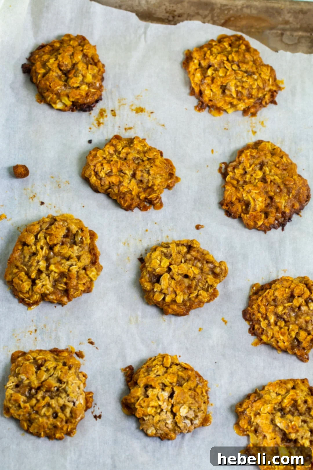 Freshly baked Apple Toffee Oatmeal Cookies cooling on a baking sheet, ready for glazing.