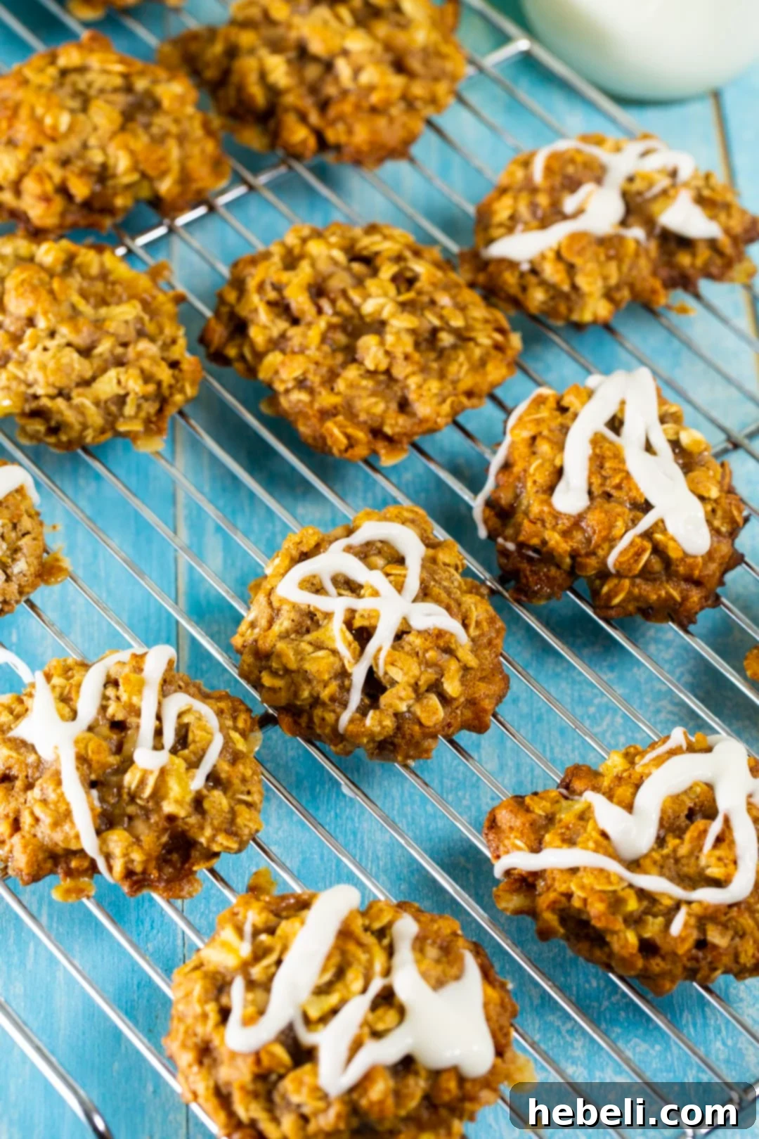 A smooth, sweet glaze being drizzled over warm Apple Toffee Oatmeal Cookies.