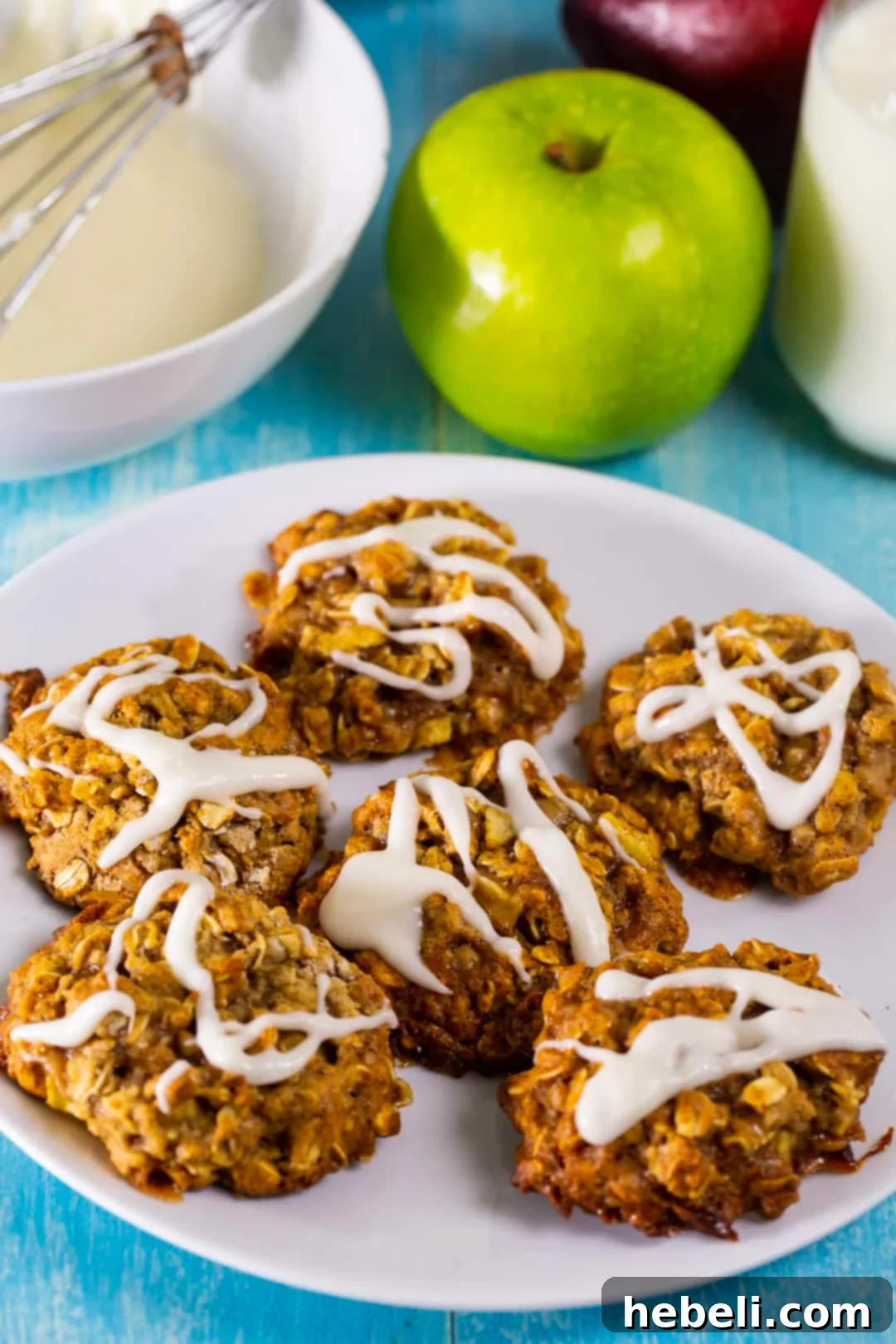 A stack of glazed Apple Toffee Oatmeal Cookies displayed beautifully on a white plate.