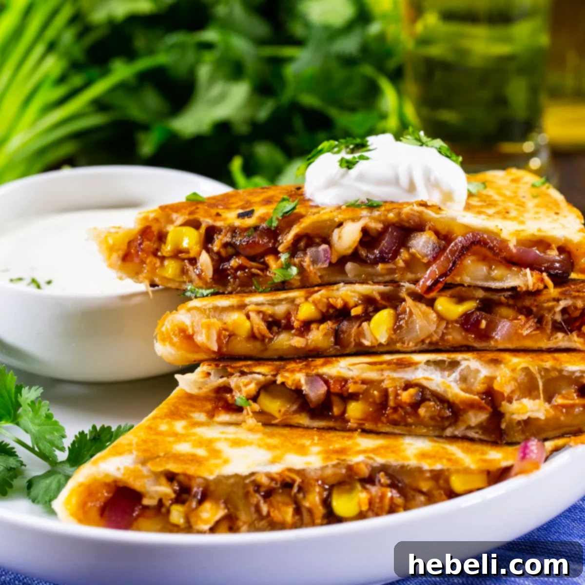 Loaded BBQ Chicken Quesadillas 2 Delicious BBQ Chicken Quesadilla cut into wedges and topped with cooling sour cream, ready to serve.