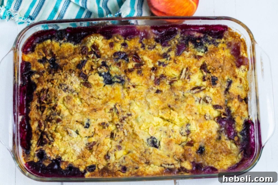 Freshly baked Blueberry Peach Dump Cake, glowing golden brown and bubbling with fruit, straight from the oven in its glass baking dish.