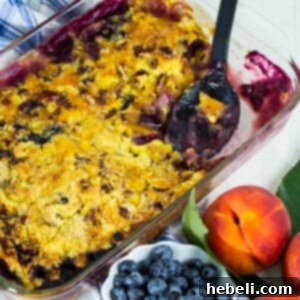 A top-down view of a serving of Blueberry Peach Dump Cake, highlighting its perfectly golden crust and vibrant fruit filling.