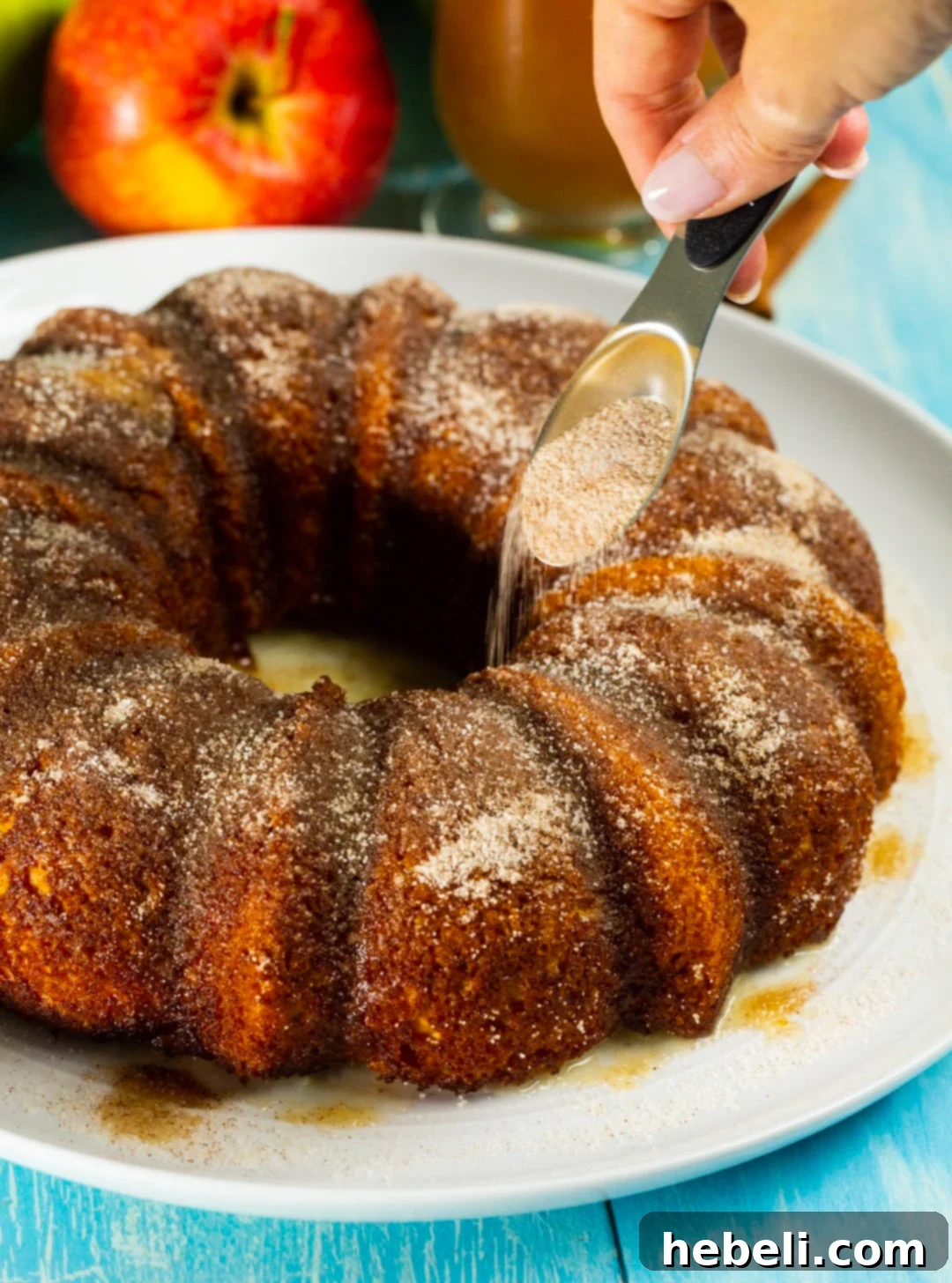 Granulated sugar and cinnamon being generously sprinkled over a freshly baked Apple Cider Bundt Cake.