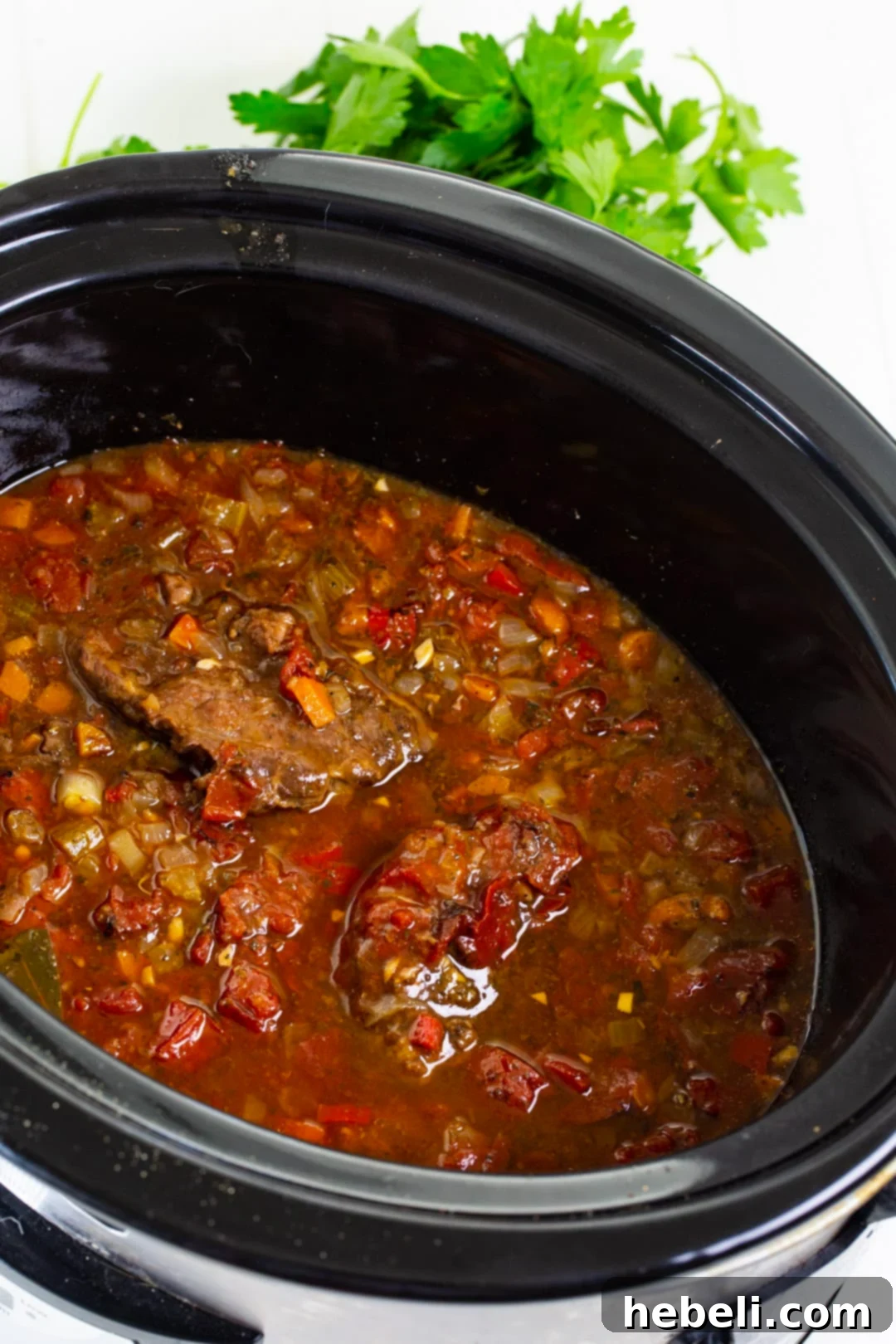 Fork Tender Slow Cooker Grillades 3 Grillades simmering gently in a crock pot, showcasing the rich gravy and tender meat.