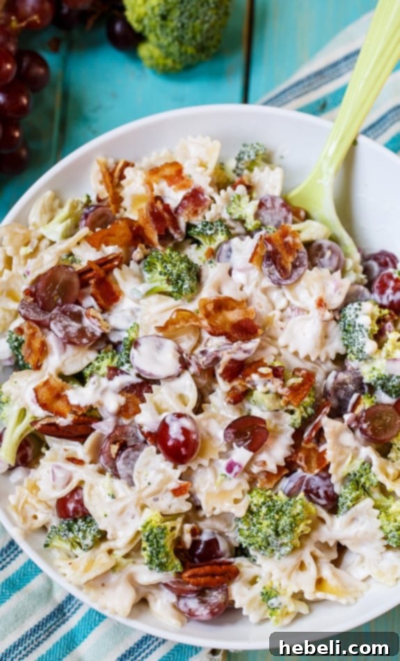 Sweet & Savory Broccoli Grape Pasta Medley 2 A large white bowl filled with vibrant Broccoli Grape Pasta Salad, featuring red grapes, crispy bacon, and green broccoli.