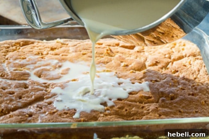 Pouring the luscious three-milk mixture over a freshly baked Tres Leches Cake, ready for soaking.