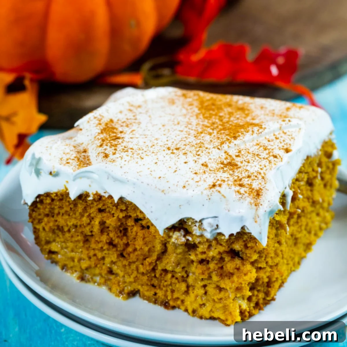 Spiced Pumpkin Tres Leches Cake 2 A delectable slice of Pumpkin Tres Leches Cake elegantly presented on a plate, highlighting its moist texture and creamy topping.