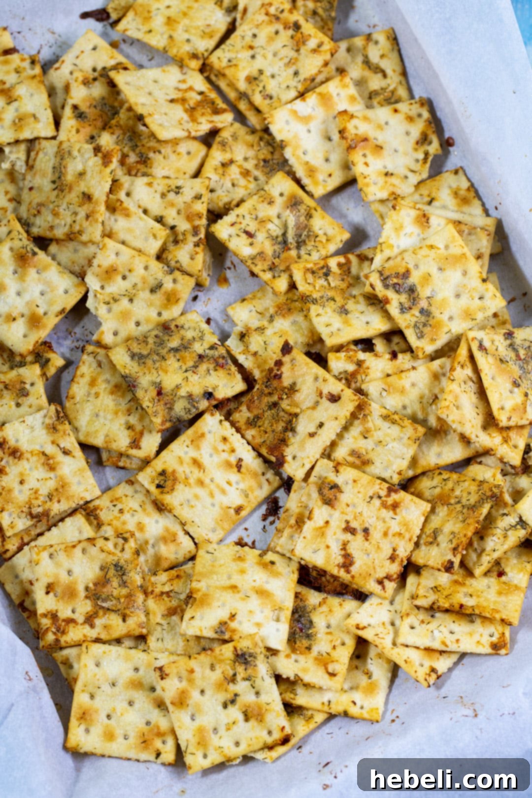 Crispy Dill Pickle Saltine crackers spread out evenly on a parchment-lined baking sheet, ready for baking.
