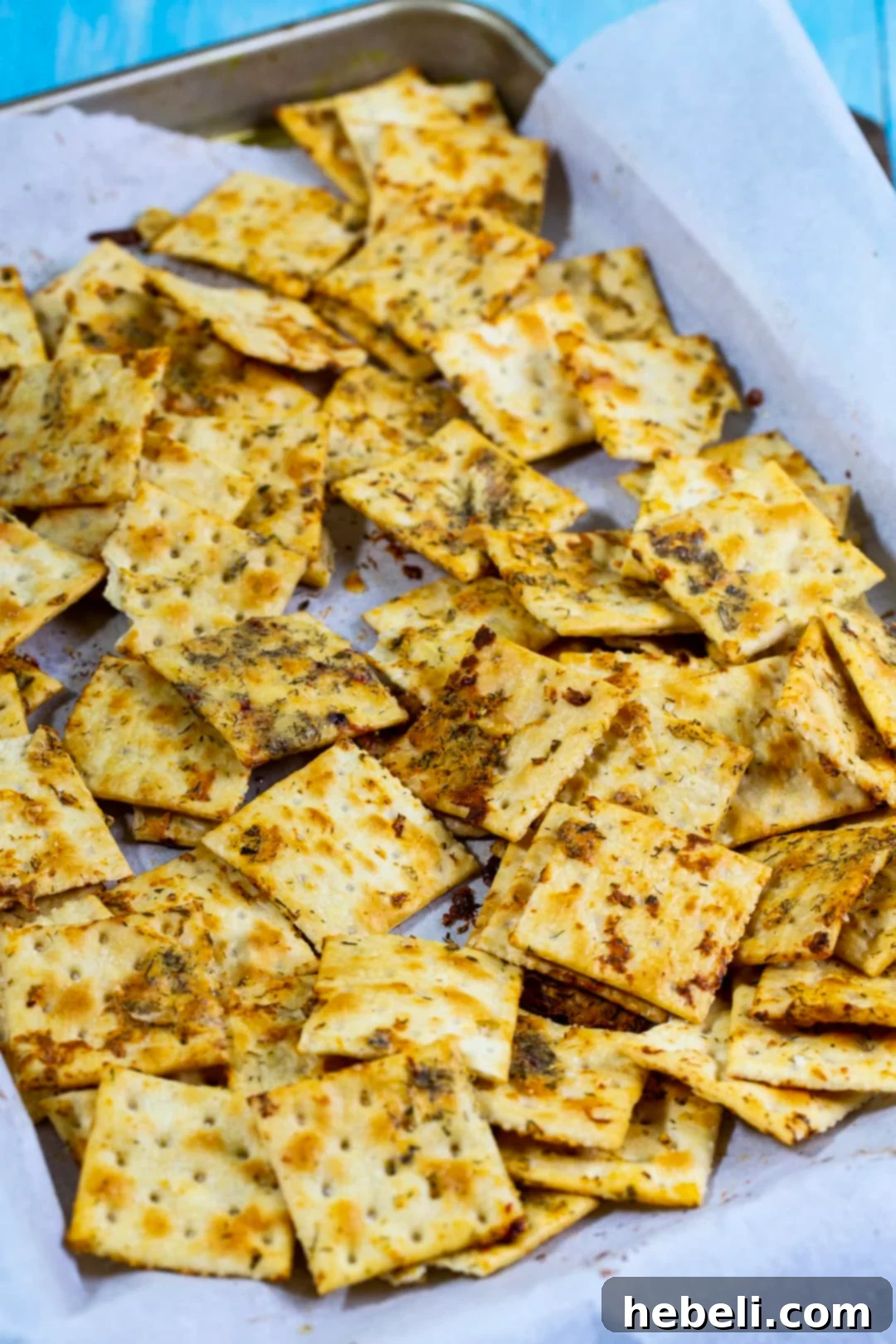 Freshly baked Dill Pickle Saltines cooling on a baking sheet, glistening with their flavorful coating.