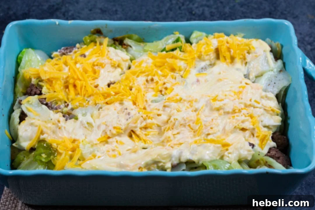Comforting Beef and Cabbage Casserole 4 Creamy soup and cheese mixture being spread evenly over the Cabbage Ground Beef Casserole base.