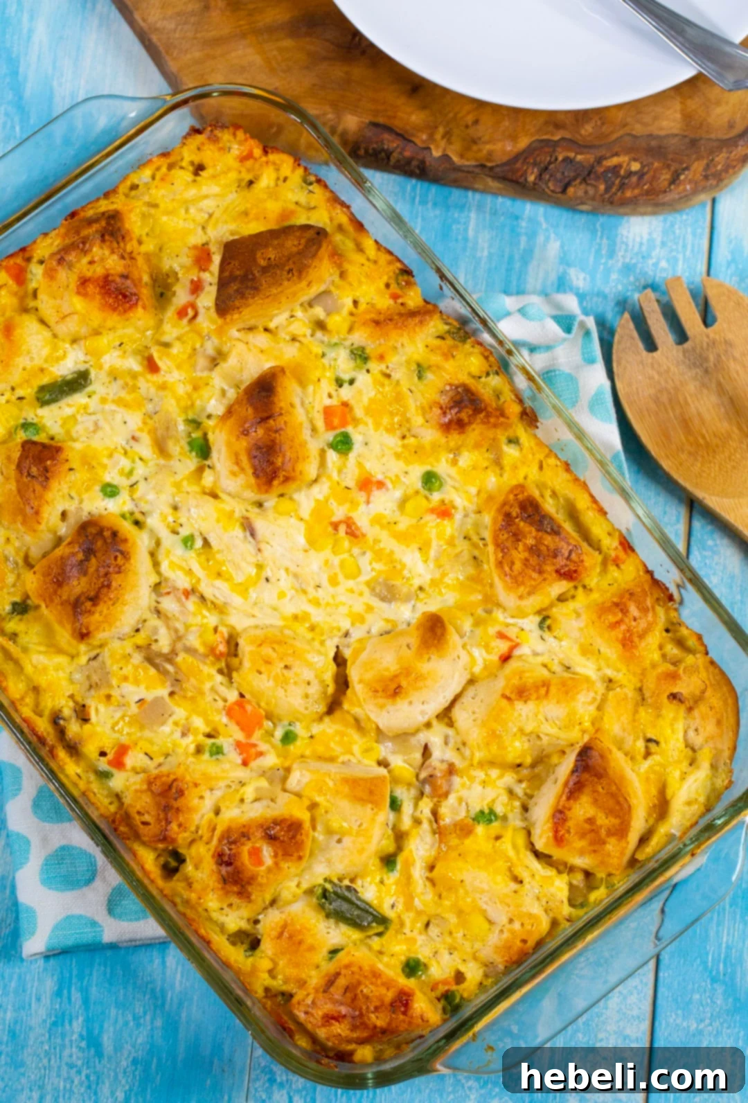 Fluffy-Topped Chicken Pot Pie Casserole 3 Overhead view of a savory chicken casserole in a baking dish, revealing the rich filling and emerging biscuit pieces before baking.