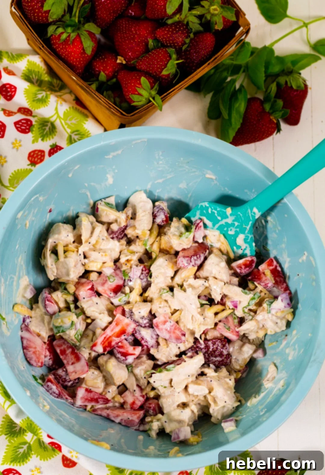 Strawberry Chicken Salad being mixed in a large bowl, highlighting the vibrant colors of the ingredients.