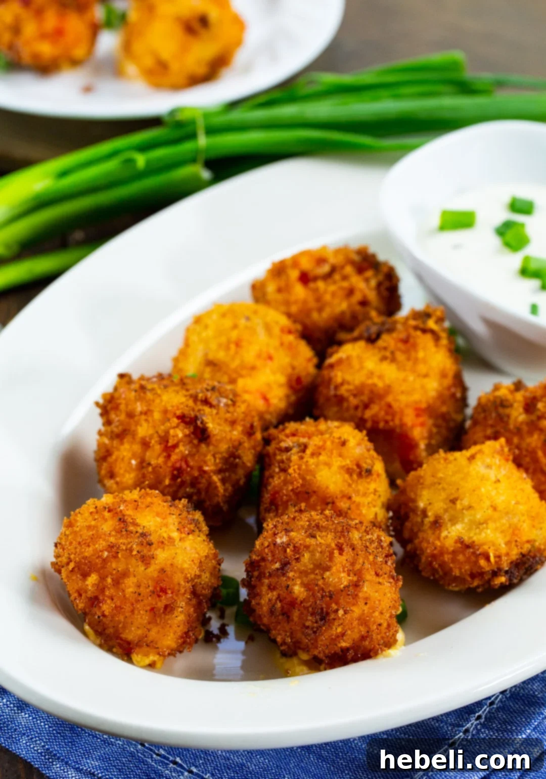 Crispy Pimento Cheese Bites with Creamy Ranch 3 A plate of freshly fried Pimento Cheese Balls alongside a small bowl of creamy Ranch dressing, ready to be served.