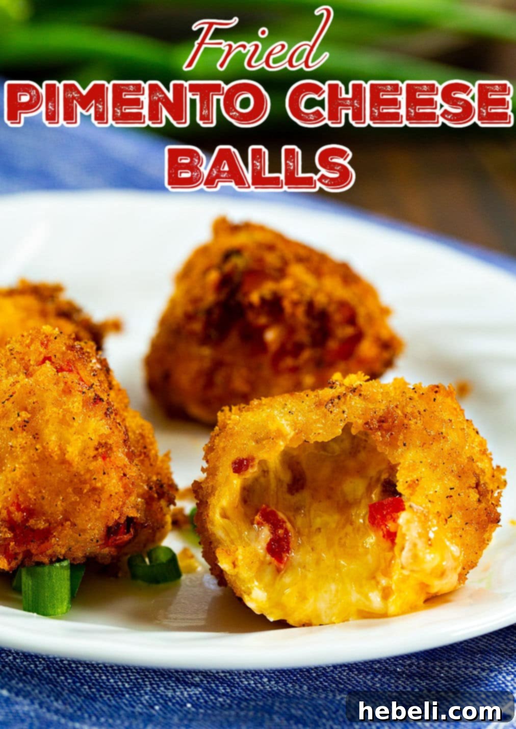 Crispy Pimento Cheese Bites with Creamy Ranch 4 A close-up of a Fried Pimento Cheese Ball on a plate with a bite taken out, showing the melted pimento cheese inside.