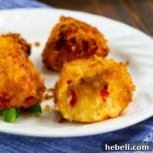 A top-down view of golden-brown Fried Pimento Cheese Balls on a rustic wooden board, garnished with fresh herbs, ready to be served.