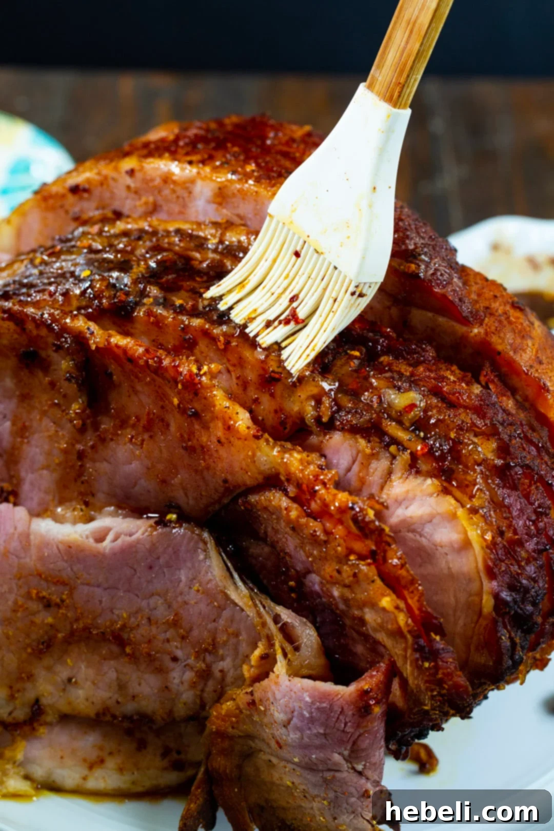 Slow Cooker Hot Honey Glazed Ham 4 Ham being brushed with a vibrant honey glaze, ready for serving.