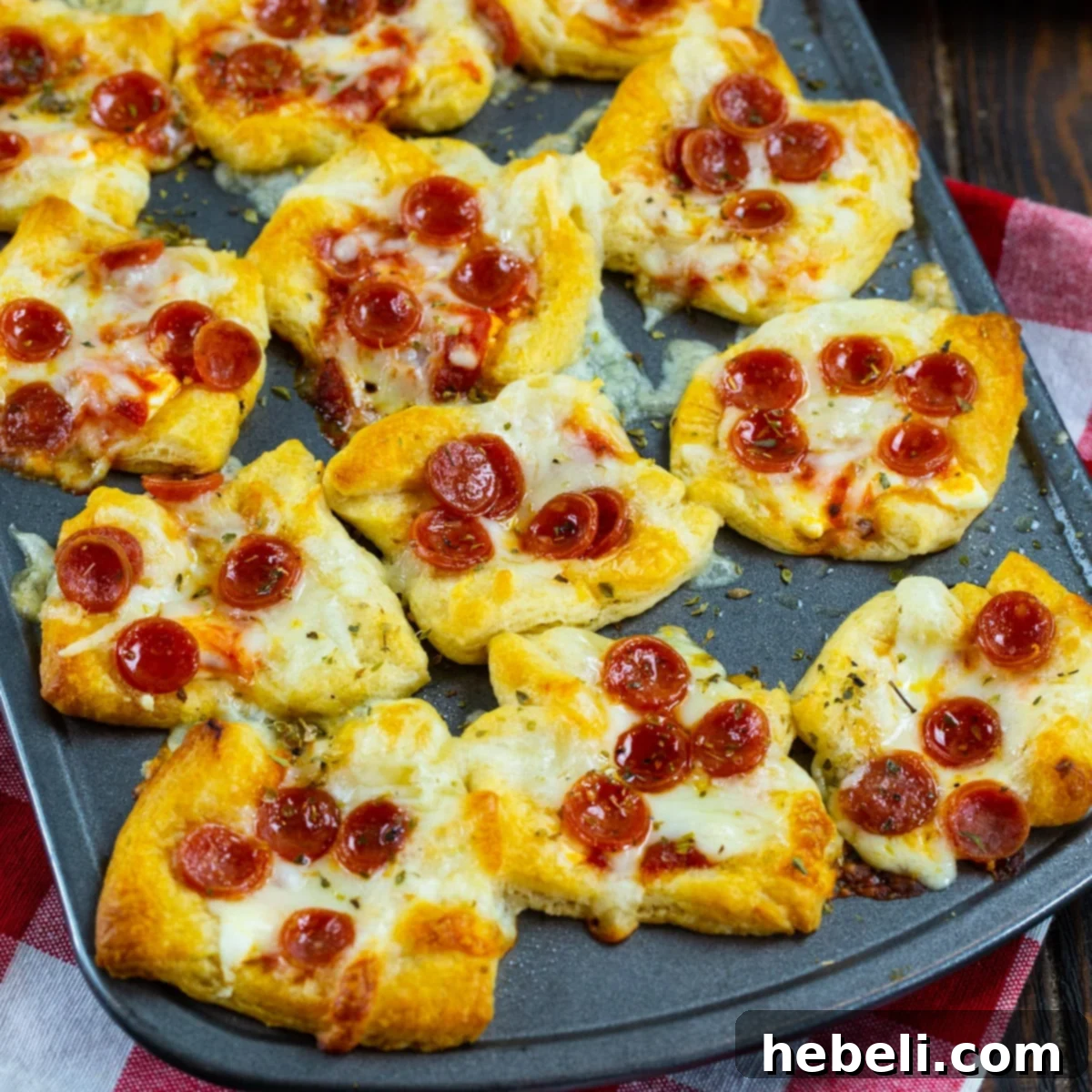 Cheesy Pepperoni Pizza Bites 2 Golden brown Pepperoni Pizza Poppers nestled in a mini muffin tin, steam gently rising, ready to be served.
