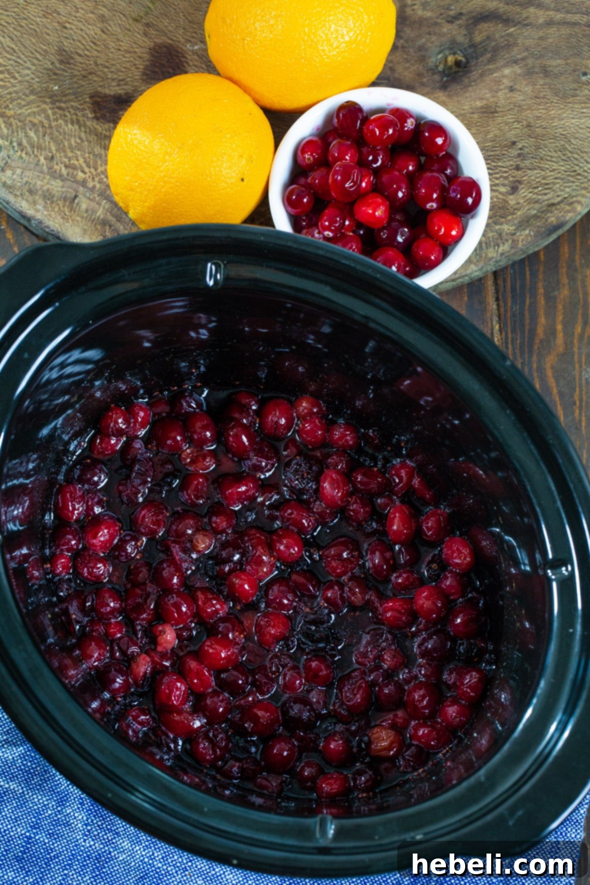 Homemade Slow Cooker Cranberry Sauce 3 Fresh cranberries and ingredients simmering in a slow cooker, transforming into delicious sauce.