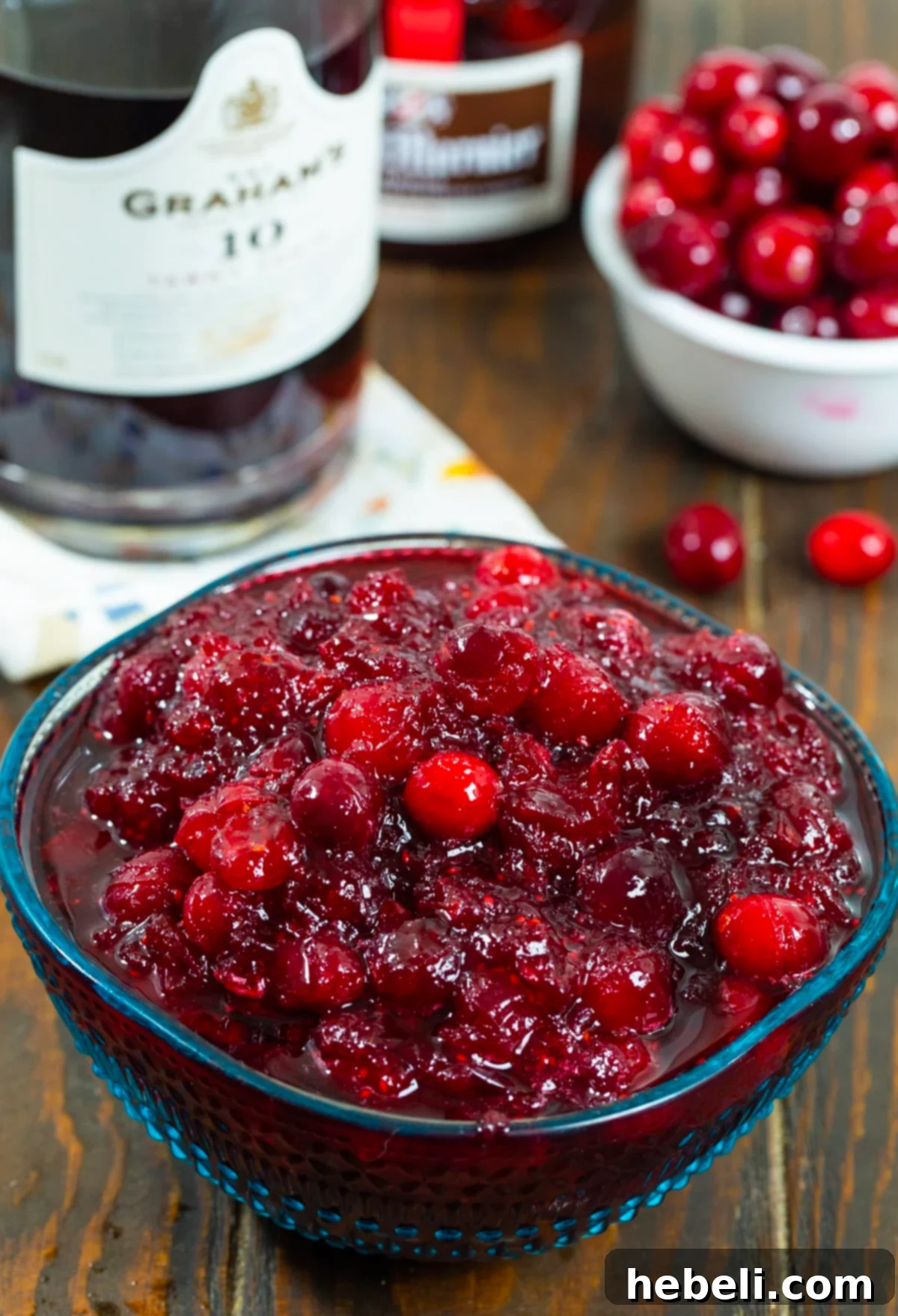 Cranberry Bourbon Relish 4 A bowl of Boozy Cranberry Sauce with a bottle of port wine in the background, highlighting the key alcoholic ingredient.