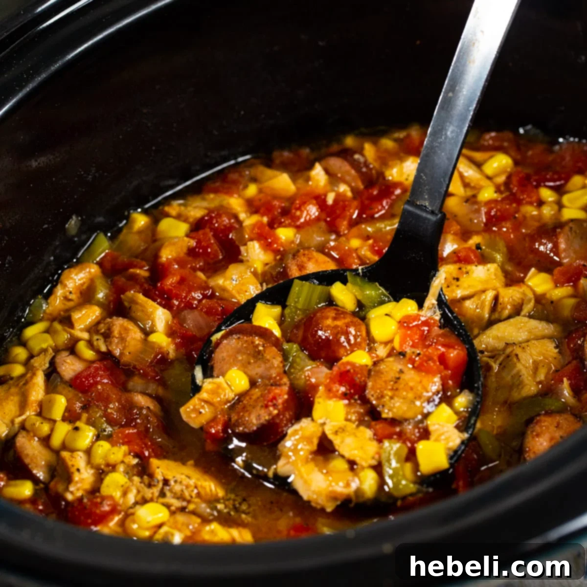 Ladle scooping slow cooker Cajun turkey soup out of slow cooker, showcasing its rich texture and ingredients.