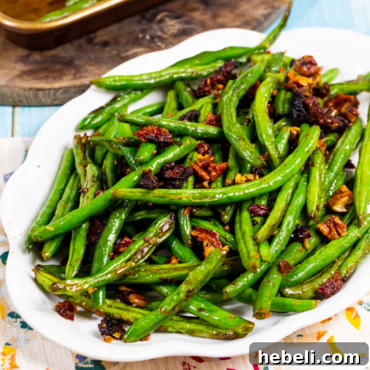 Mediterranean Roasted Green Beans with Sun-Dried Tomatoes 2 Perfectly roasted green beans with sun-dried tomatoes and pecans arranged on a white serving plate, ready to be enjoyed.