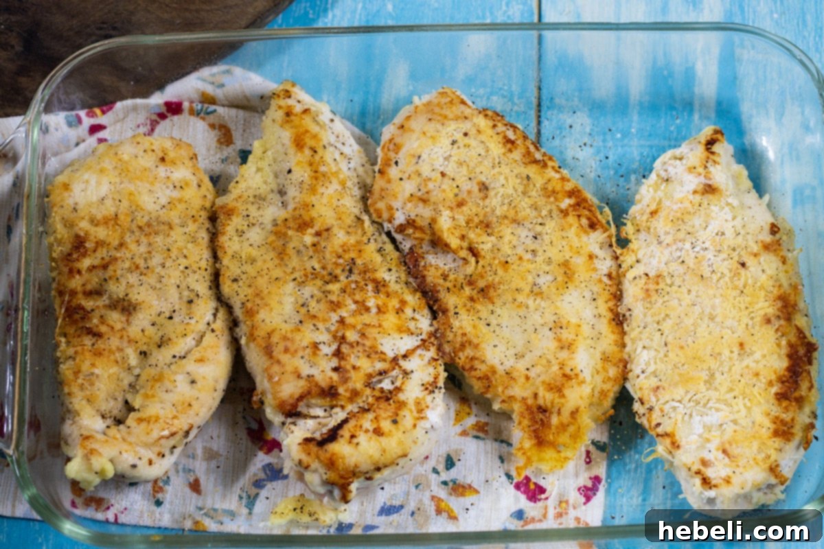 The Company Coop 3 Sauteed chicken breasts arranged in a baking dish, ready for topping with vegetables and cheese.