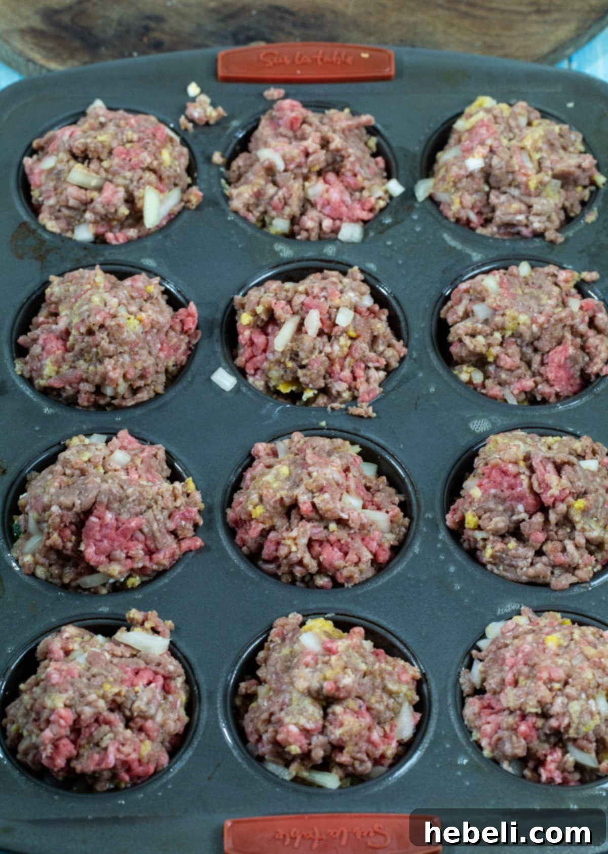 Unbaked Jalapeno Popper Meatloaf Muffins nestled in a muffin tin, ready for the oven.