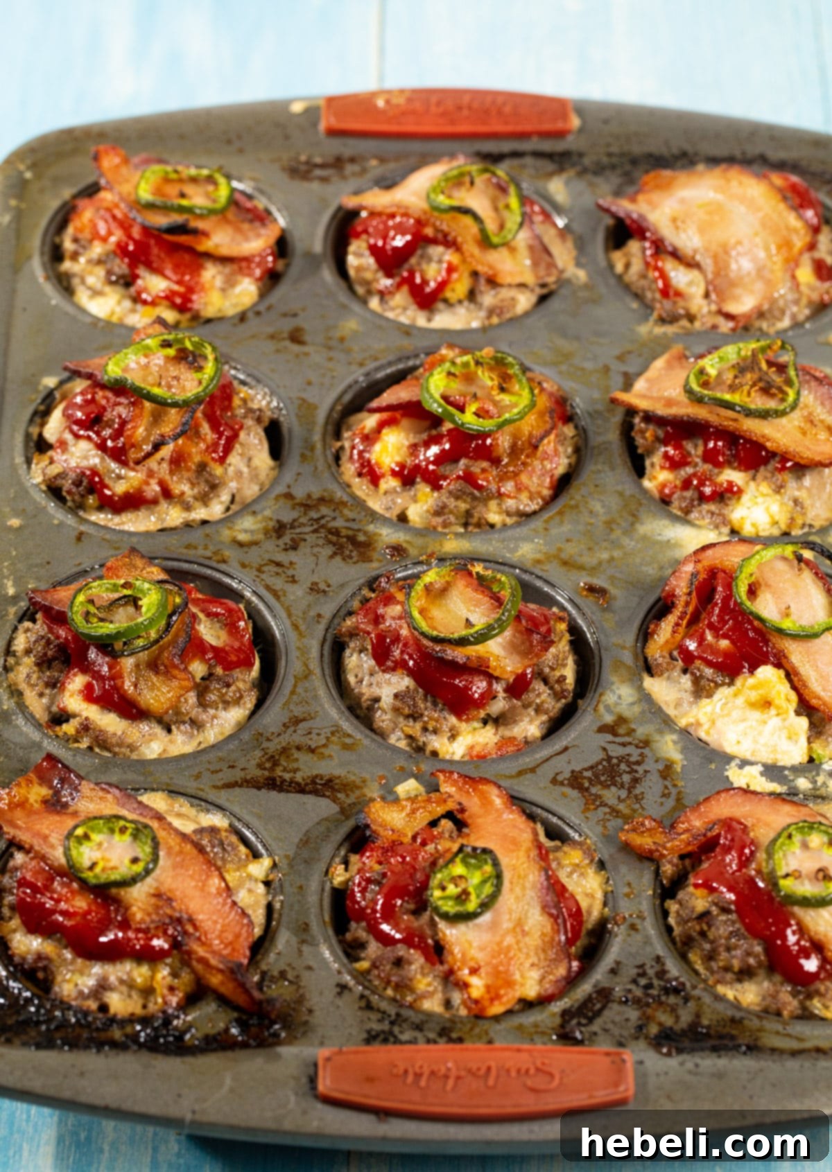 Two freshly baked Jalapeno Popper Meatloaf Muffins, golden brown and glistening, after being removed from the oven.