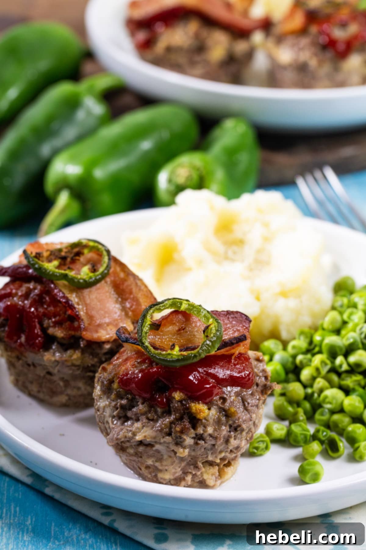 Two perfectly baked and garnished Jalapeno Popper Meatloaf Muffins on a clean white plate.