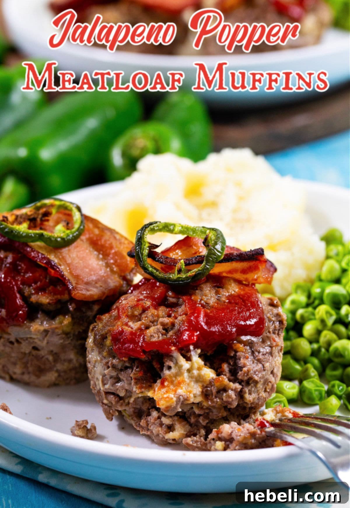 A plate featuring two Jalapeno Popper Meatloaf Muffins, accompanied by a scoop of mashed potatoes and a side of green peas, showcasing a complete meal.