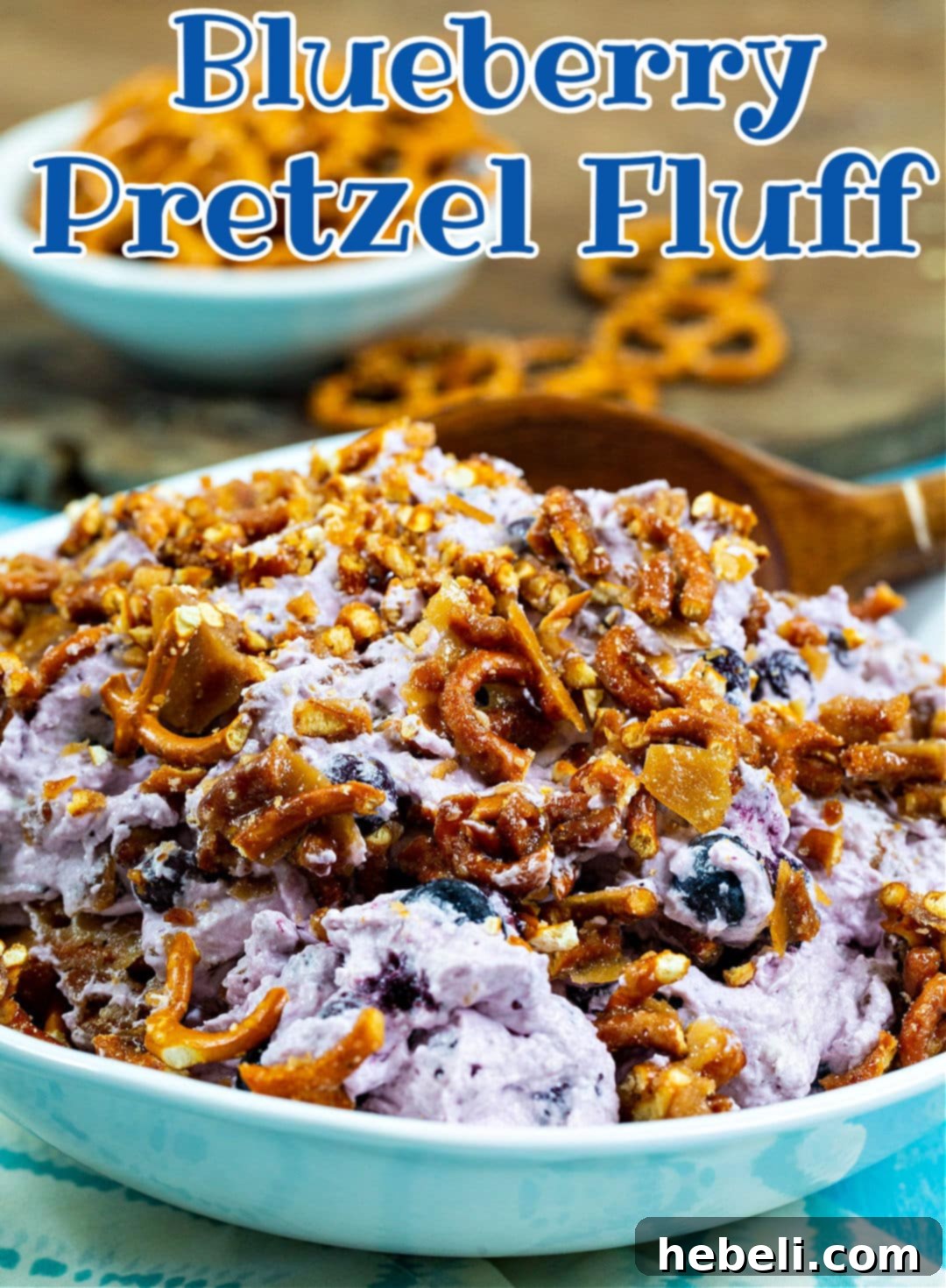 Creamy Blueberry Pretzel Crunch 5 Spoon scooping a generous portion of Blueberry Pretzel Fluff from a serving bowl.