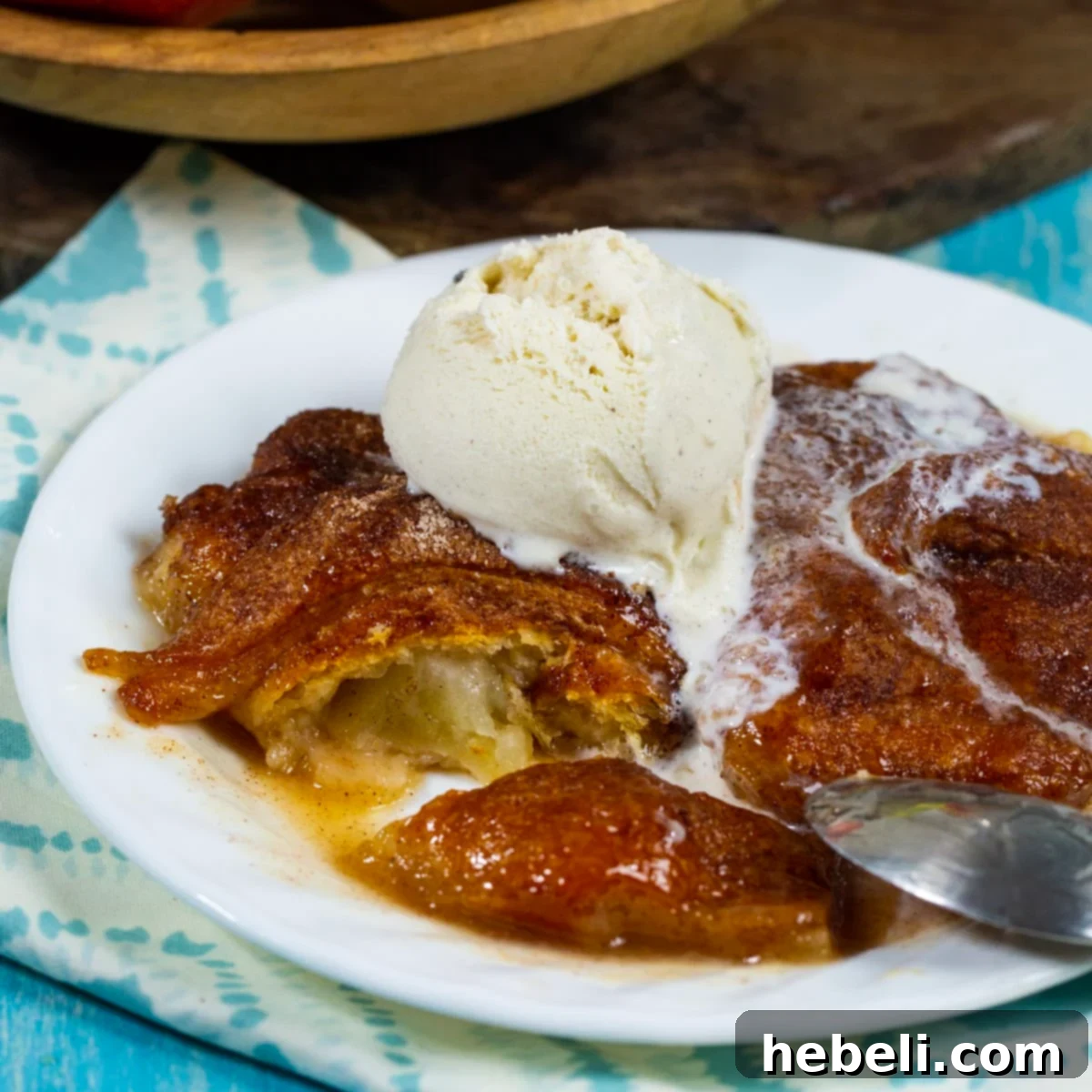 Blazing Apple Dumplings 2 Fireball Apple Dumplings topped with a scoop of creamy vanilla ice cream, showcasing the golden-brown crust and glistening sauce.