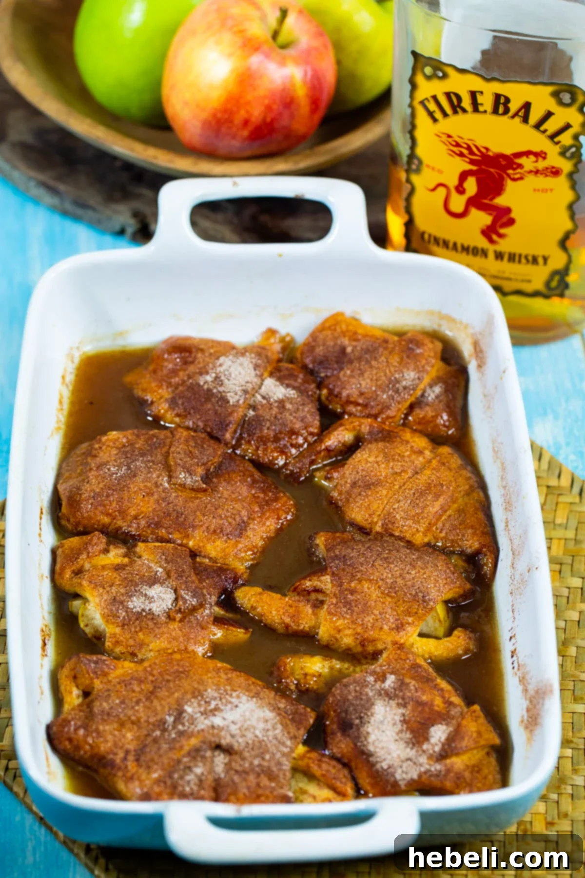 Blazing Apple Dumplings 3 Close-up shot of golden-brown Fireball Apple Dumplings bubbling in a baking dish, surrounded by the rich, caramelized sauce.