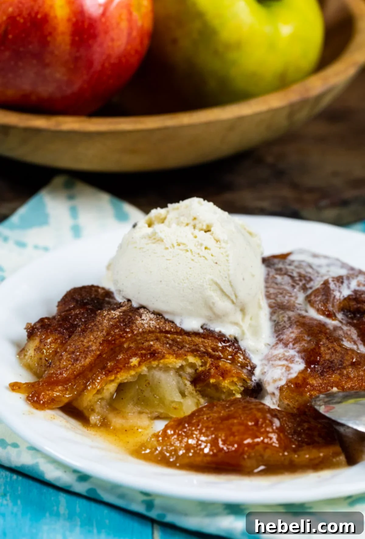 Blazing Apple Dumplings 4 A Fireball Apple Dumpling with a section cut out, revealing the tender apple slice wrapped in golden crescent dough, bathed in rich caramel sauce.