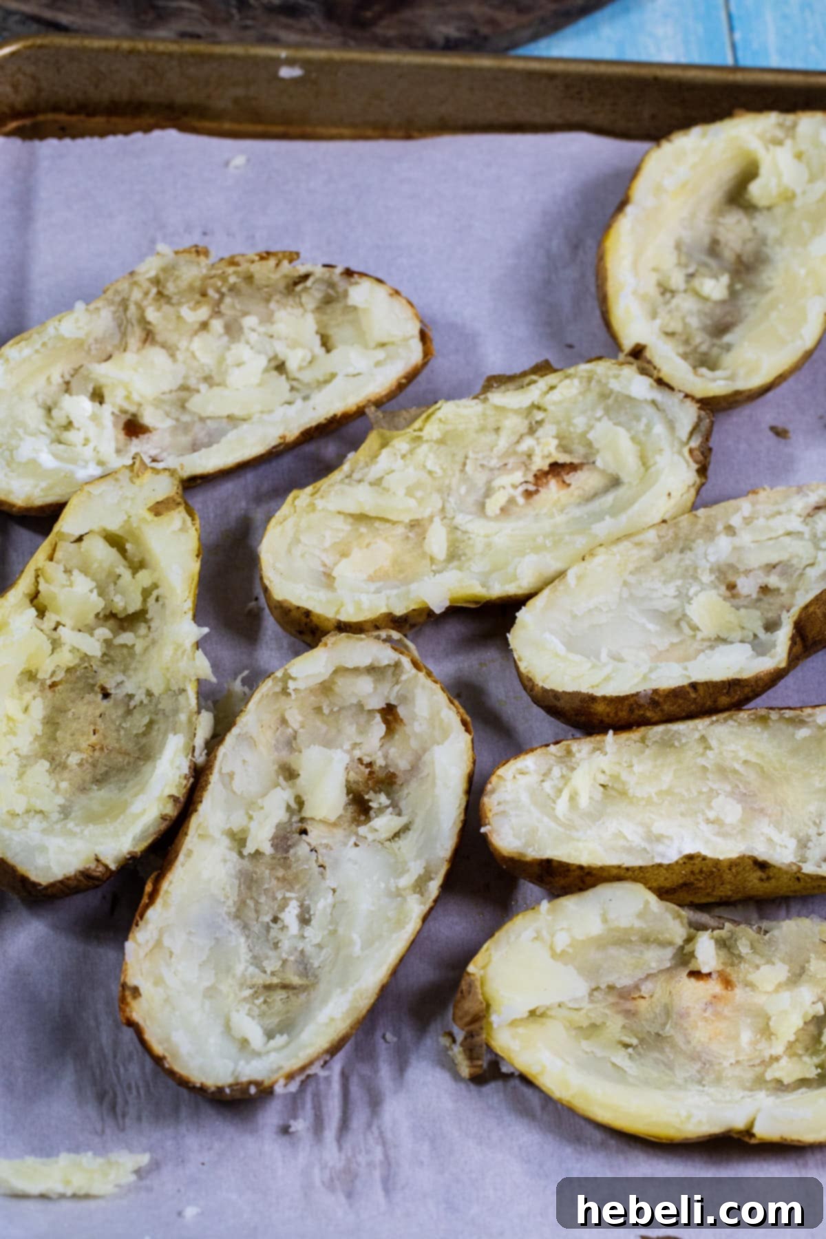 Hollowed-out potato halves neatly arranged on a baking sheet, showcasing the empty skins.