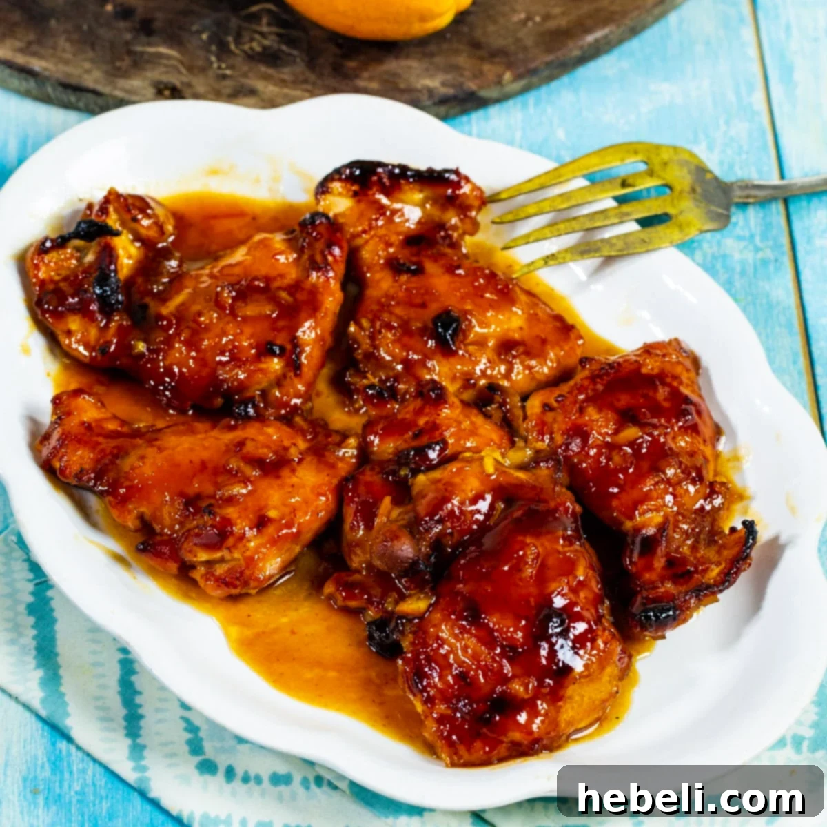 Perfectly baked BBQ Orange Baked Chicken on a rustic serving platter, garnished for a delicious meal.