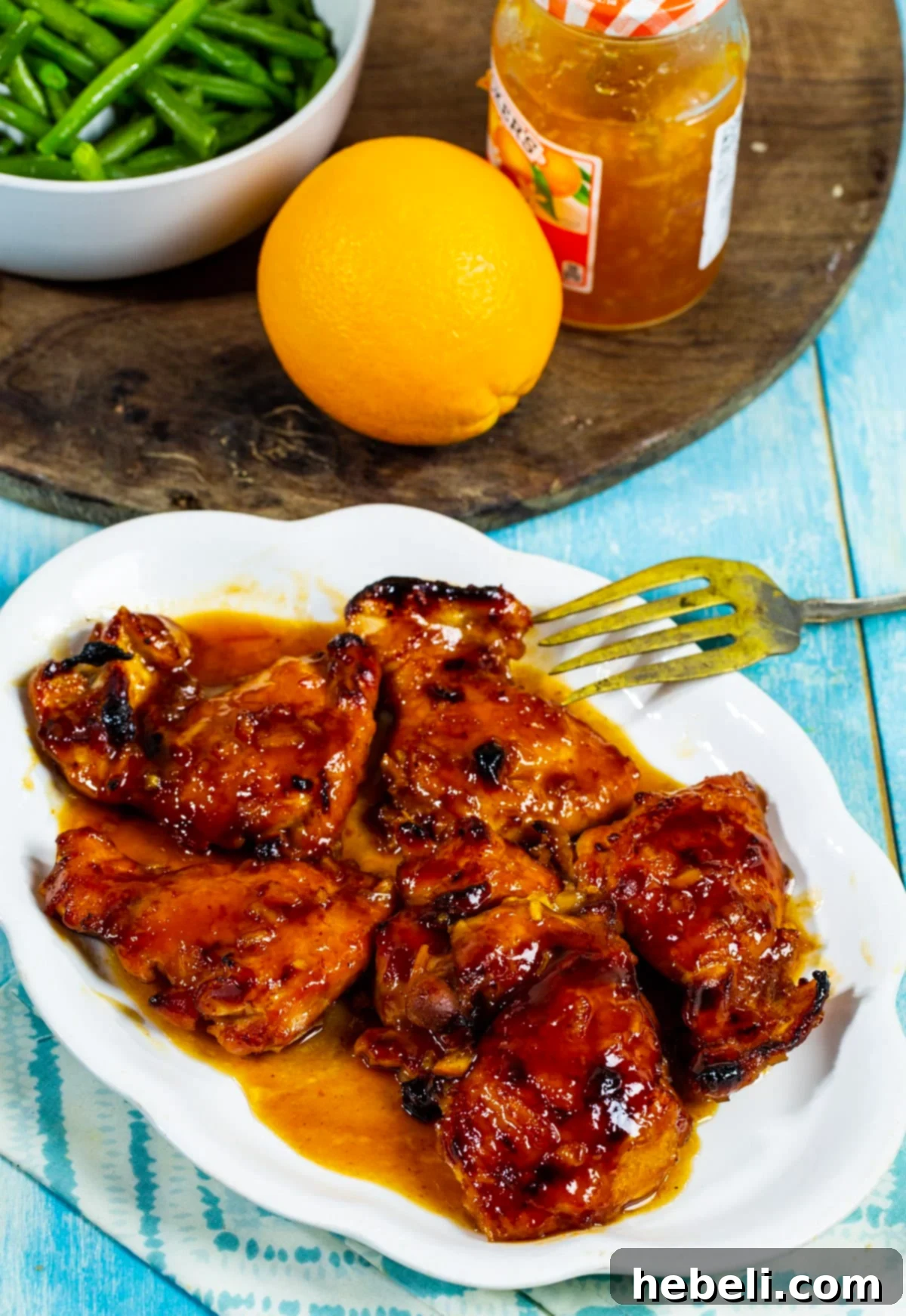 Close-up of baked chicken, golden brown and coated in a glossy BBQ orange sauce, ready to be served.