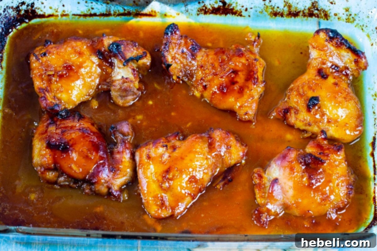 Baked BBQ Orange Chicken golden brown and bubbling with sauce in a baking dish, fresh from the oven.