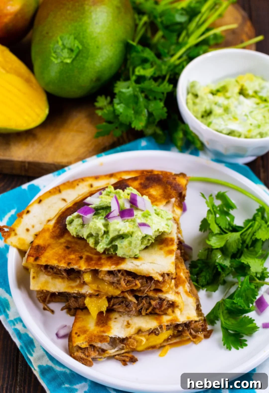 Island BBQ Pork and Mango Quesadillas 5 Delicious BBQ Pork and Mango Quesadilla triangles stacked on a plate with fresh cilantro.