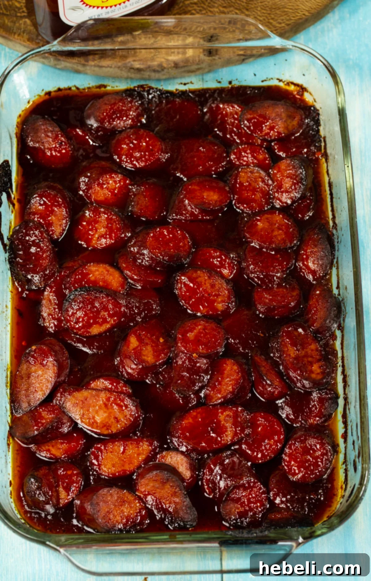 Cooked sausage slices in a baking pan, coated in a sticky, caramelized BBQ sauce.